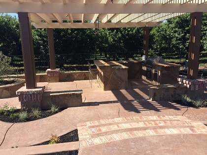 stamped concrete backyard patio with pergola and kitchen